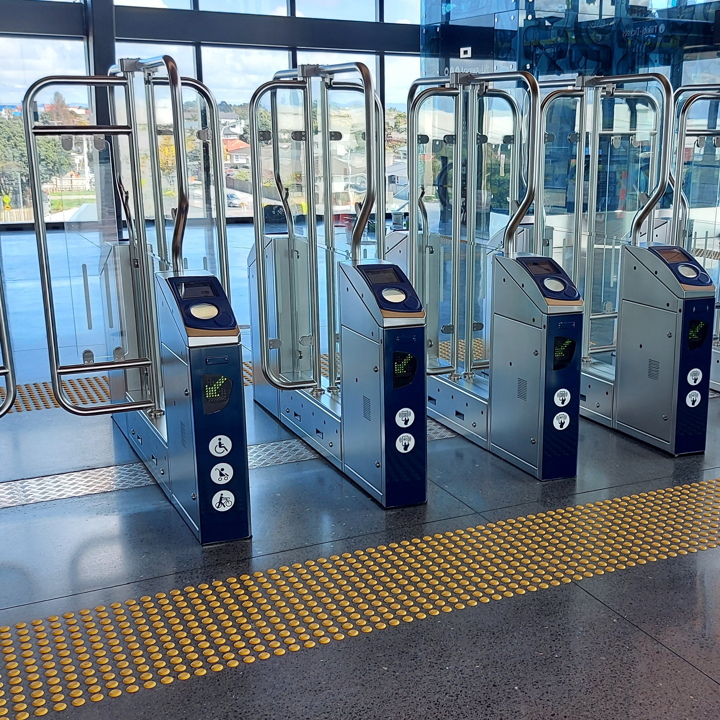 TacPro yellow polyurethane tactile indicator warning studs on both sides of train station tag on turnstiles