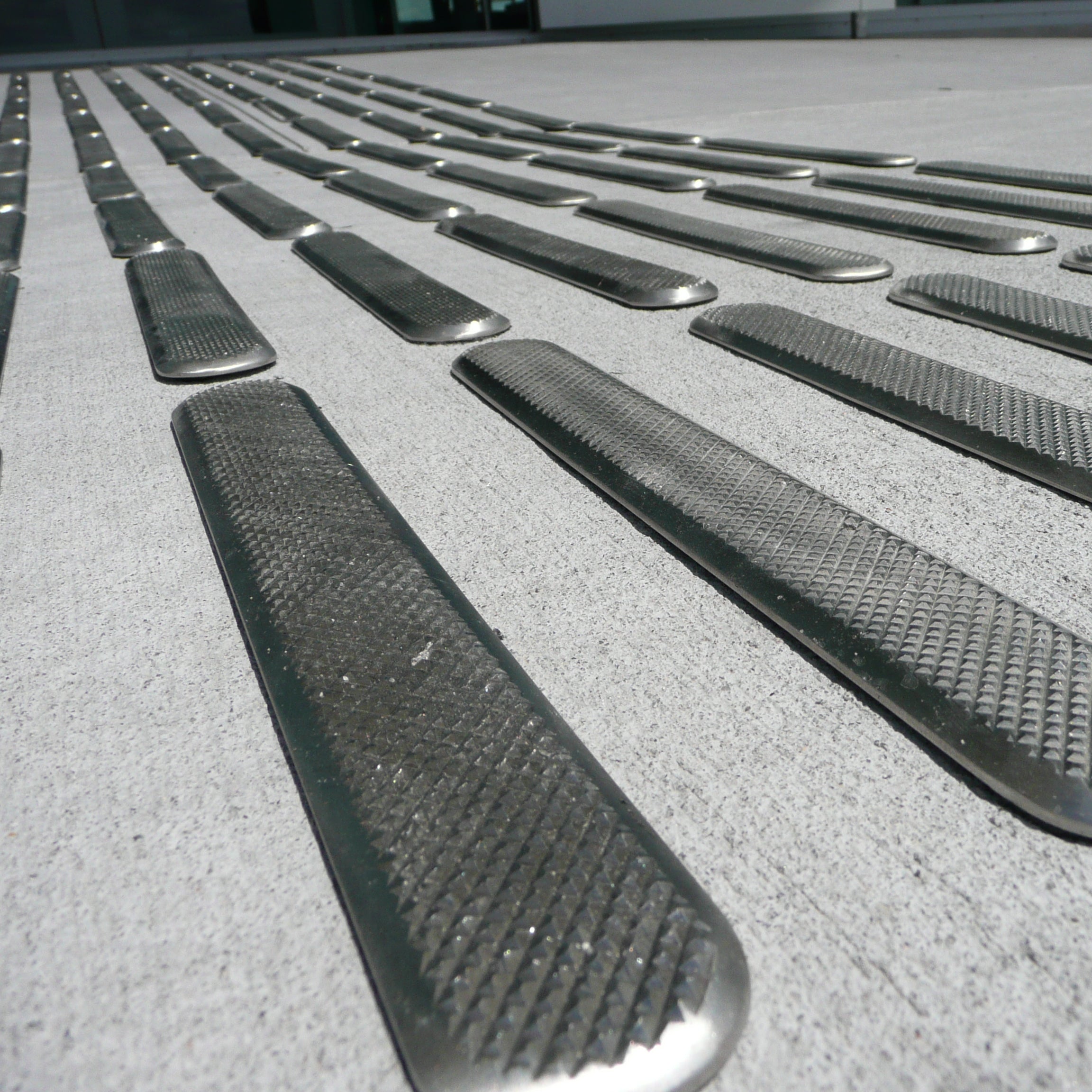 Close-up of TacPro stainless steel tactile directional indicators installed to concerete.