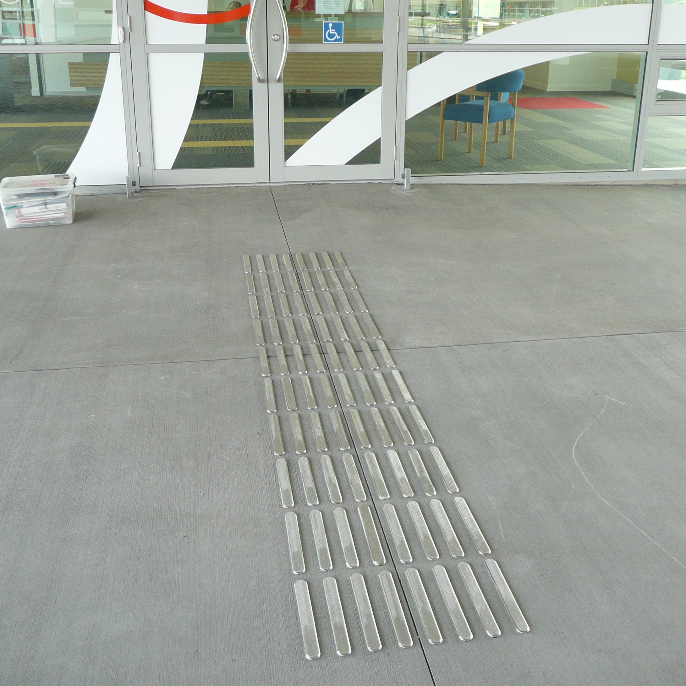 TacPro stainless steel tactile directional indicators installed to concrete leading to a school main entrance door