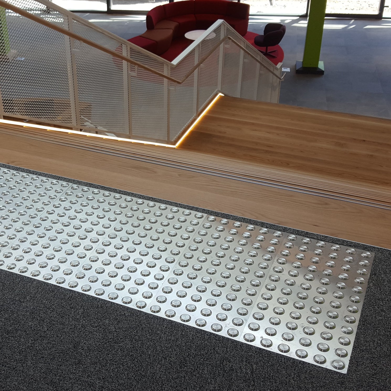 TacPro stainless steel tactile indicator warning plates on dark carpet at the top of timber stairs