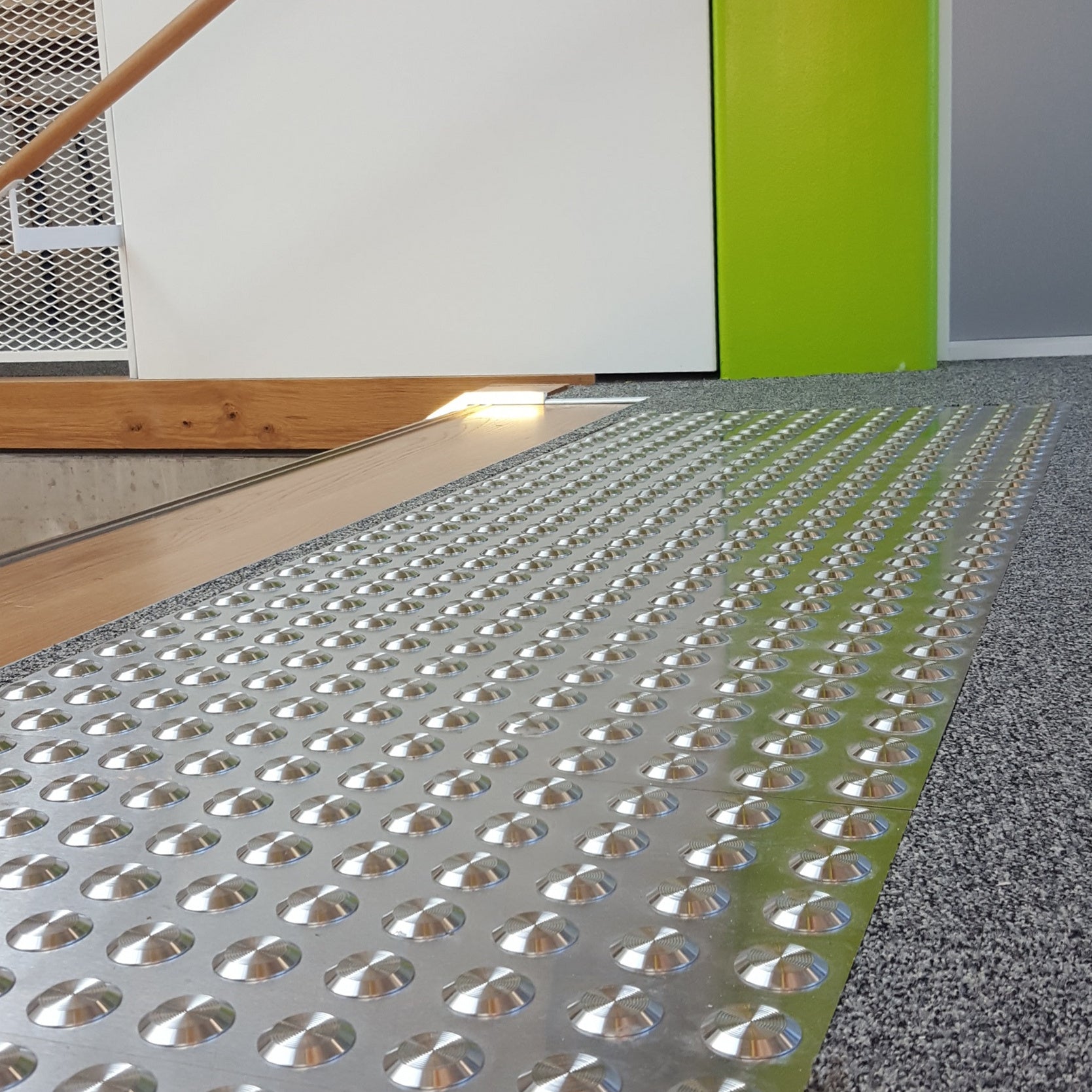 TacPro stainless steel tactile indicator warning studs on carpet at the top of timber stairs