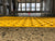Close-up of TacPro yellow peel-and-stick tactile indicator warning tiles on polished concrete at train station ticket gate