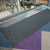 TacPro black peel-and-stick warning tactile tiles installed on multi-coloured carpet at the top of stairs at a school.